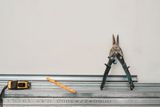 Metallprofile für den Trockenbau mit Blechschere und Maßband an einer Wand